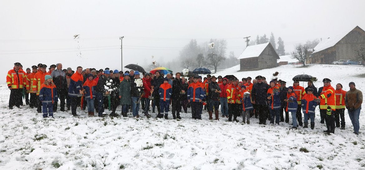 Spatenstich bei Schneegestöber mit vielen Menschen, vor allem Feuerwehrleute