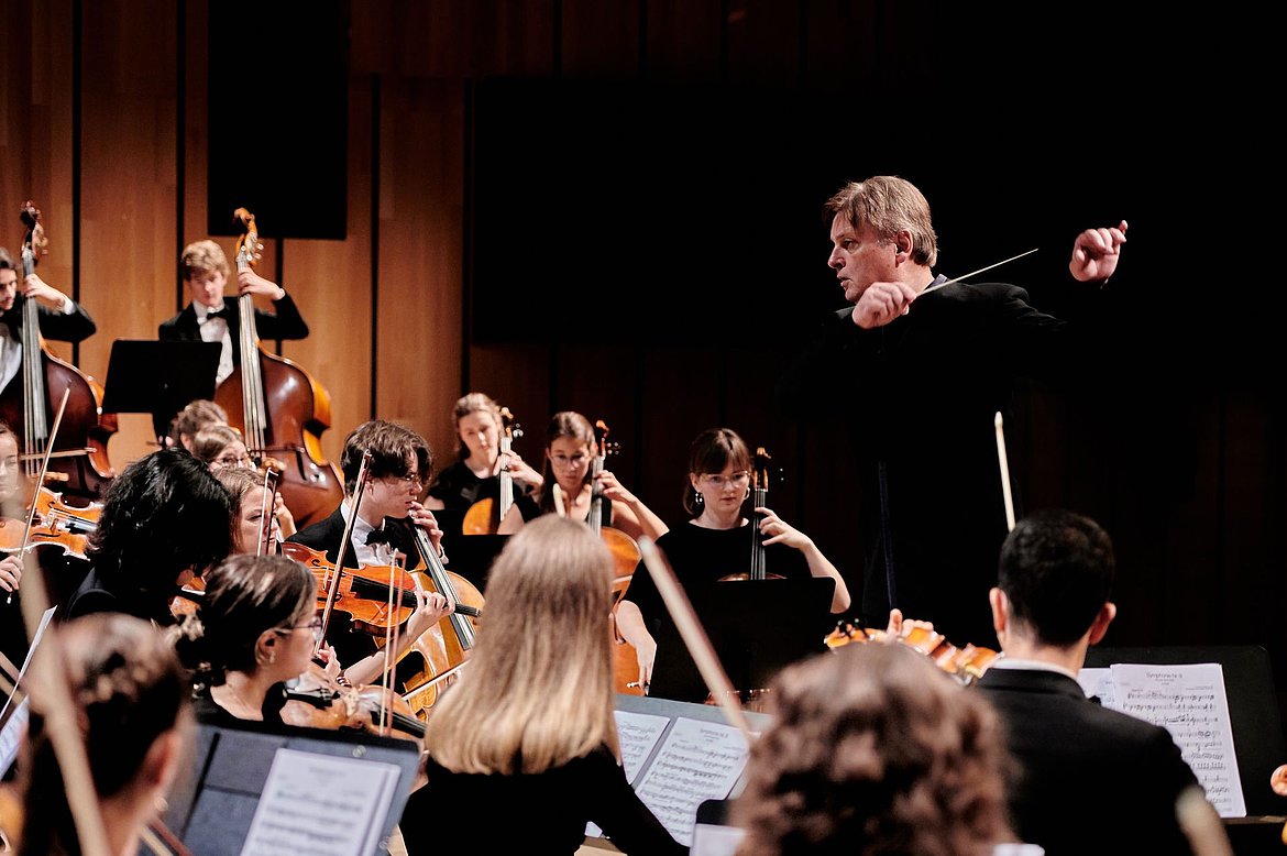 Ein Dirigent dirigiert ein Symphonieorchester aus jungen Leuten.