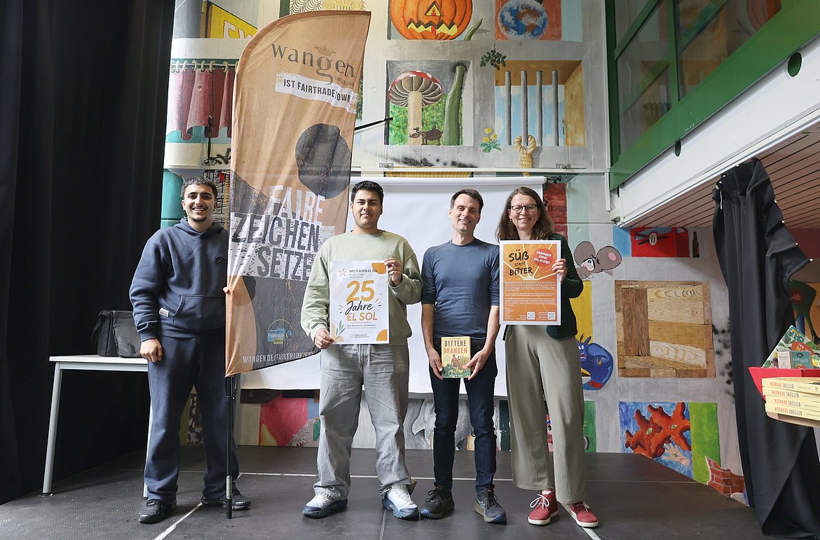 Vier Personen mit Plakaten für 25 Jahre El Sol und Bittere Orangen.