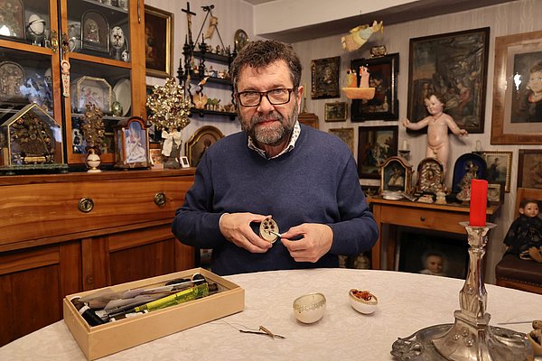 Ein Mann mit einem halbe Ei in der Hand in seiner Stube. 