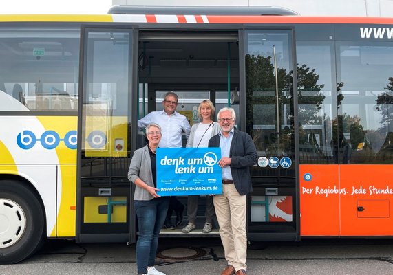 Zwei Männer und zwei Frauen zeigen Plakat
