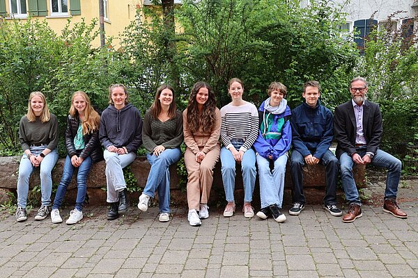 Schülerinnen und Schüler und JMS-Leiter Dr. Hans Wagner sitzen nebeneinander