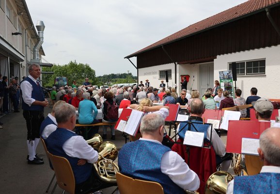 Blick über die Musikkapelle Primisweiler und viele Menschen an Biertischen