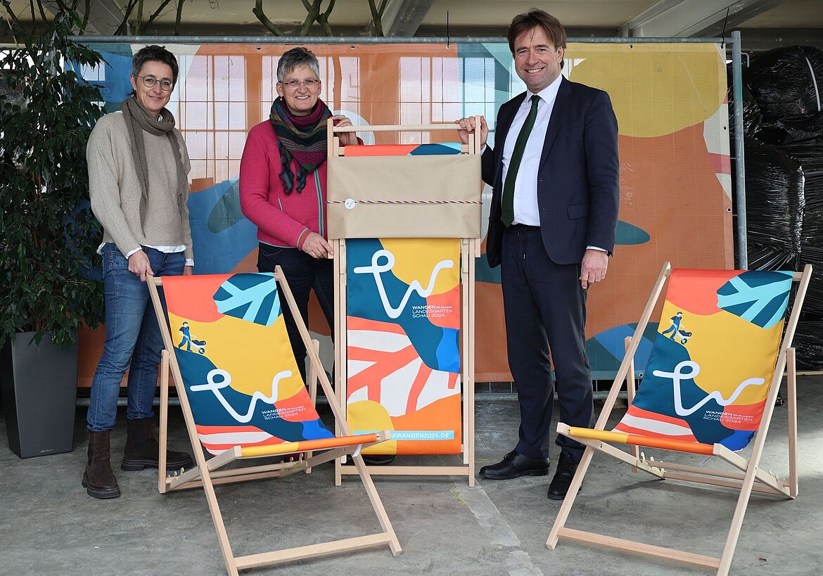 Drei Personen und bunte Liegestühle der Landesgartenschau 2024.