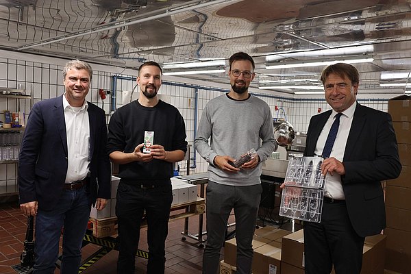 Vier Männer stehen nebeneinander mit Schokoladenformen in der Hand.