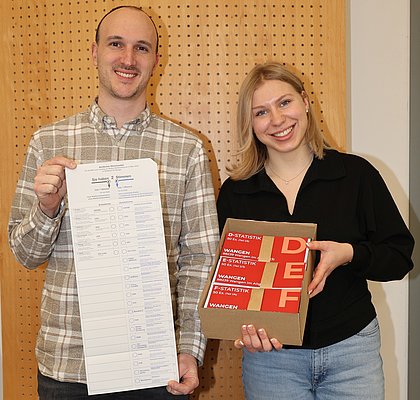Ein Mann und eine Frau zeigen Wahlscheine.