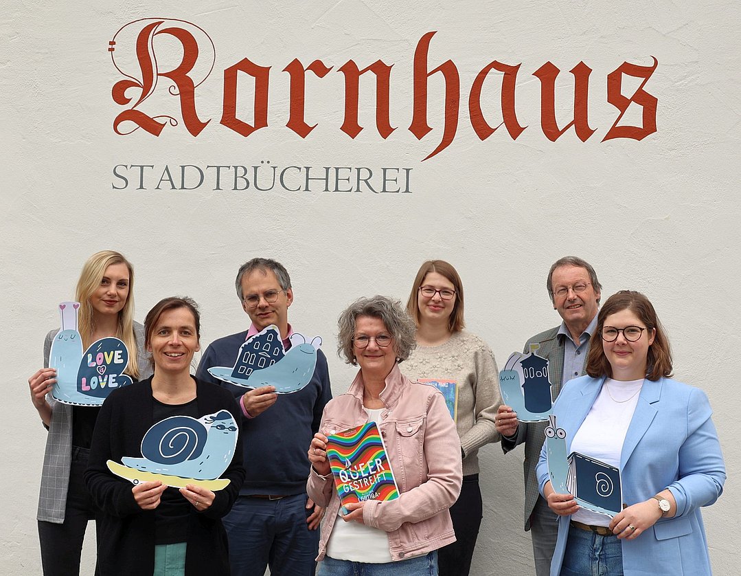 Die Projektpartner halten eine Schnecke aus Papier hoch. Sie ist das Maskottchen der Baden-Württembergischen Kinder- und Jugendliteraturtage.