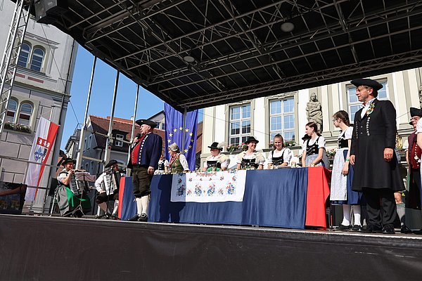Glockenspielergruppe flankiert von Oberbürgermeister Michael Lang und dem Vizepräsidenten des Deutschen Trachtenverbands Gunter Dlabal